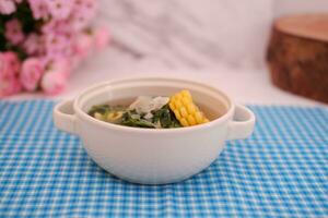 Sayur Bening Daun kelor jagung or Moringa Oleifera clear soup with sweet corn served in bowl photo