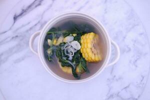 Sayur Bening Daun kelor jagung or Moringa Oleifera clear soup with sweet corn served in bowl photo