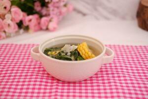 Sayur Bening Daun kelor jagung or Moringa Oleifera clear soup with sweet corn served in bowl photo