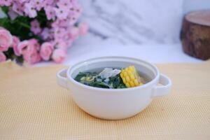 Sayur Bening Daun kelor jagung or Moringa Oleifera clear soup with sweet corn served in bowl photo