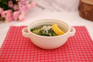 Sayur Bening Daun kelor jagung or Moringa Oleifera clear soup with sweet corn served in bowl photo