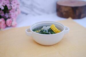 Sayur Bening Daun kelor jagung or Moringa Oleifera clear soup with sweet corn served in bowl photo