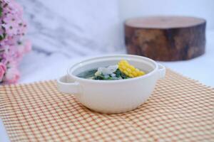 Sayur Bening Daun kelor jagung or Moringa Oleifera clear soup with sweet corn served in bowl photo