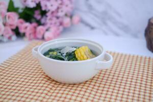Sayur Bening Daun kelor jagung or Moringa Oleifera clear soup with sweet corn served in bowl photo
