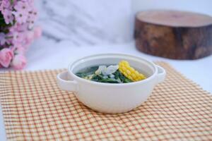 Sayur Bening Daun kelor jagung or Moringa Oleifera clear soup with sweet corn served in bowl photo
