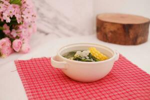 Sayur Bening Daun kelor jagung or Moringa Oleifera clear soup with sweet corn served in bowl photo