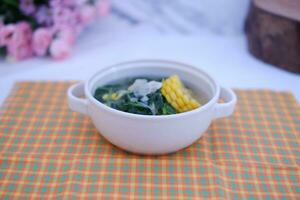 Sayur Bening Daun kelor jagung or Moringa Oleifera clear soup with sweet corn served in bowl photo