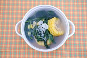 Sayur Bening Daun kelor jagung or Moringa Oleifera clear soup with sweet corn served in bowl photo