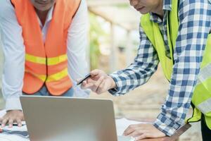 Engineers team use laptop and check the blueprint on site. Contractor and inspector inspection construction during project.civil Forman check quality assurance. Audit, inspect, quality control. photo