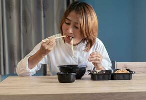 mujer sentado a silla disfrutar comiendo delicioso conjunto caja comida teniendo para llevar a hogar relajante descansando y contento estilo de vida conceptos foto