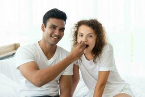 Smiling and happy couple having dessert in bed in the morning photo