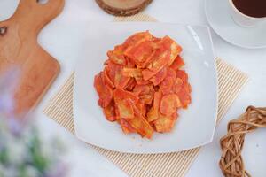 Keripik singkong balado or balado cassava chips on a serving plate, it tastes spicy, sweet and crunchy photo