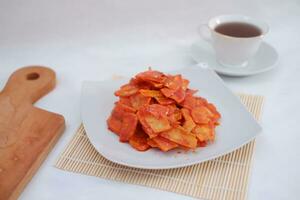 Keripik singkong balado or balado cassava chips on a serving plate, it tastes spicy, sweet and crunchy photo