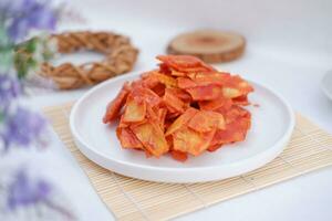 Keripik singkong balado or balado cassava chips on a serving plate, it tastes spicy, sweet and crunchy photo