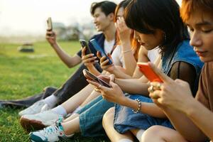 Image of a group of young Asian people laughing together and using their phones photo