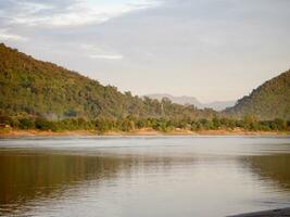 nubes terminado lago, un vibrante puesta de sol terminado un sereno lago, con vistoso reflexiones reluciente en el agua, natural paisaje terminado un corriente corriendo a río con bosque y montaña, mekong río foto