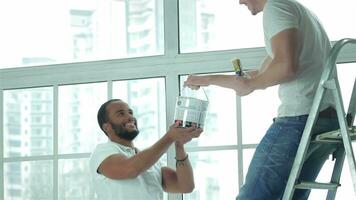 A Man takes the paint to another man on the ladder video