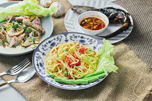 Delicious Thai food on the table in a restaurant in Thailand, papaya salad, larb, waterfall, sticky rice. photo