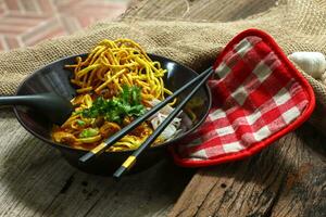 Noodles with pork and vegetables in a bowl on the table, Khao Soi Kai, Northern Style Curried Noodle Soup with choice of pickled chicken photo