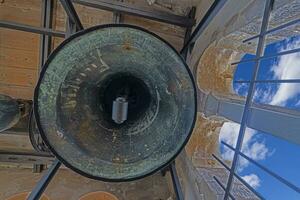 Picture of bronze bells in a bell tower of a historic church in Kratia from ground perspective photo