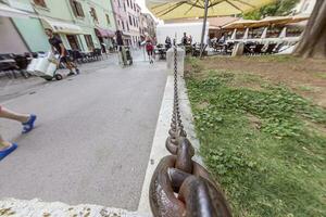 Picture along an iron chain that acts as a partition between the footpath and a green area photo