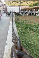 Picture along an iron chain that acts as a partition between the footpath and a green area photo