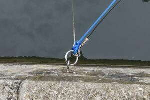 Picture of an eyelet for mooring ships at the pier with a line in front of dark water photo