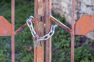 Close-up of a lock with a chain that closes a metal gate photo