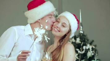 Beautiful couple in Santa hat holding sparklers in hand and kiss video