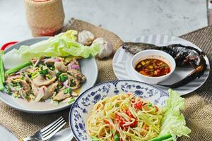 Delicious Thai food on the table in a restaurant in Thailand, papaya salad, larb, waterfall, sticky rice. photo