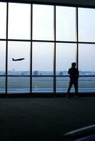 silueta de un hombre en pie en frente de el ventana a el aeropuerto foto