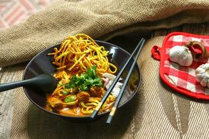 Noodles with pork and vegetables in a bowl on the table, Khao Soi Kai, Northern Style Curried Noodle Soup with choice of pickled chicken photo