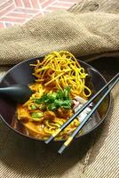 Noodles with pork and vegetables in a bowl on the table, Khao Soi Kai, Northern Style Curried Noodle Soup with choice of pickled chicken photo