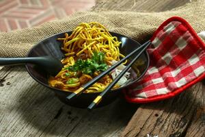 Noodles with pork and vegetables in a bowl on the table, Khao Soi Kai, Northern Style Curried Noodle Soup with choice of pickled chicken photo