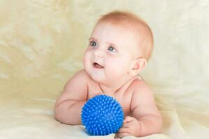 small child lying on stomach and holding ball for massage photo