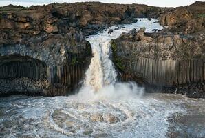 Powerful Aldeyjarfoss waterfall flowing from ancient Badardalshraun lava field and basalt column in summer at Iceland photo