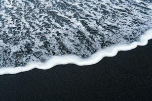 Sea wave on volcanic black sand beach in Diamond beach photo