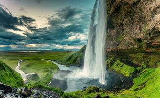 hermosa seljalandsfoss cascada fluido y lozano campo en melancólico día en verano foto