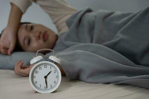 asiático mujer en cama tarde molesto a dormir sufrimiento insomnio, insomne o asustado en un pesadilla, mirando triste preocupado y estresado. cansado y dolor de cabeza o migraña despertar arriba en el medio de el noche. foto