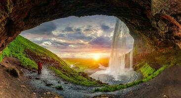 Natural cave with sunset over Seljalandsfoss waterfall flowing in summer at Iceland photo