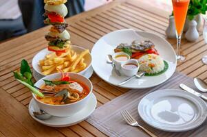 Tom yum kung spicy soup with beef steak, fish fried rice on table photo