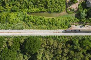 Vintage train driving on railway track in tropical forest at countryside photo