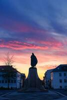 Monumento estatua de leif Erikson, un famoso islandés explorador en frente de principal entrenar el Hallgrimskirkja Iglesia en el puesta de sol foto