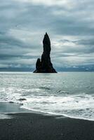 temperamental reynisdragar natural rock formación en Reynisfjara negro arena playa en atlántico Oceano a Islandia foto