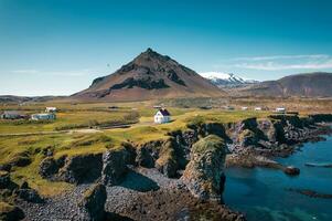 Arnarstapi fishing village with nordic house and stapafell mountain on coastline in Snaefellsnes peninsula at Iceland photo