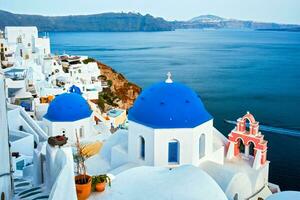 Famous view from viewpoint of Santorini Oia village with blue dome of greek orthodox Christian church photo