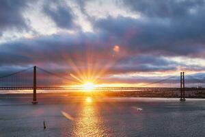 View of 25 de Abril Bridge over Tagus river at sunset. Lisbon, Portugal photo