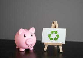 Pig piggy bank and recycling sign. Generate profit. Conserve natural resources, reduce waste, create jobs in recycling industry. Creating revenue streams through sale of recycled materials. photo