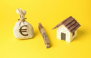 The house and the euro money bag are separated by a barrier. Stop overheating real estate market. Investment as a threat to create a market bubble. The influx of capital. High levels of debt, photo