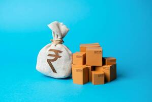 Goods boxes and indian rupee money bag. Budget purchases, large purchase orders. Global currency. Trade deal. Import and export. Profit from sales and production of goods, economic growth. photo